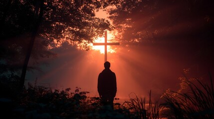 Man silhouetted against cross at sunrise with light rays