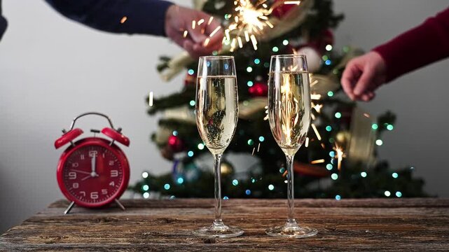 People celebrating new year's eve with champagne, sparklers, and an alarm clock showing midnight