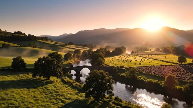 Misty sunrise over a river valley with a stone bridge and rolling green hills