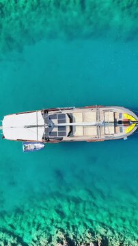 Aerial view of a wooden gulet yacht with solar panels sailing on clear turquoise water