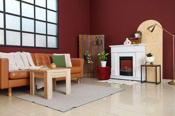 Naklejka premium Interior of stylish living room with cozy brown sofa, wooden coffee table and fireplace