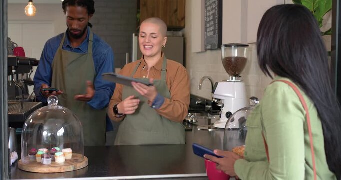 Two baristas initiating online menu at counter tapping tablet for mobile payment and brewing coffee