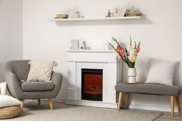 Naklejka premium Interior of living room with fireplace, armchair and gladiolus flowers