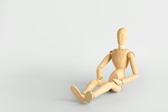 Wooden mannequin sitting on light background