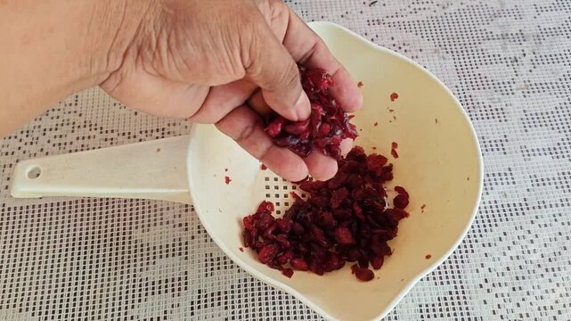 Hand picking through fresh blueberries in a white plastic strainer