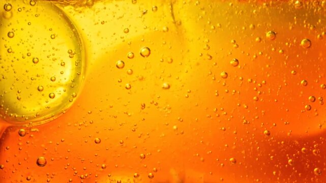 Macro closeup of fresh water drops and golden bubbles on a wet orange background creating an abstract liquid texture of cold beer foam