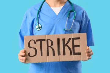 Fotobehang Natuur Park Protesting male doctor holding placard with word STRIKE on blue background, closeup  © Pixel-Shot
