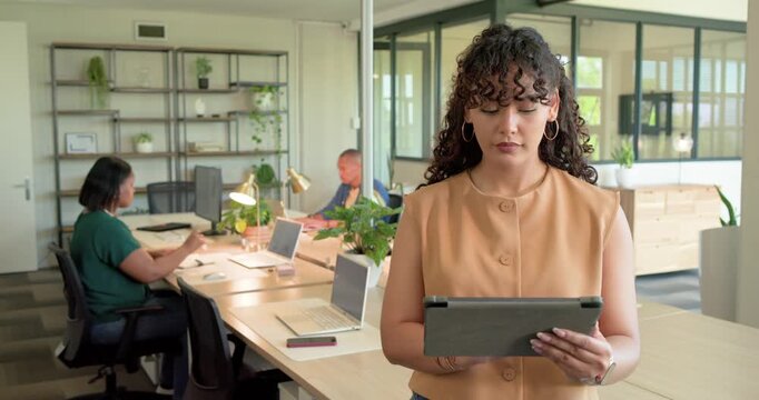 African American colleagues watching adult woman tapping tablet at shared desk checking message