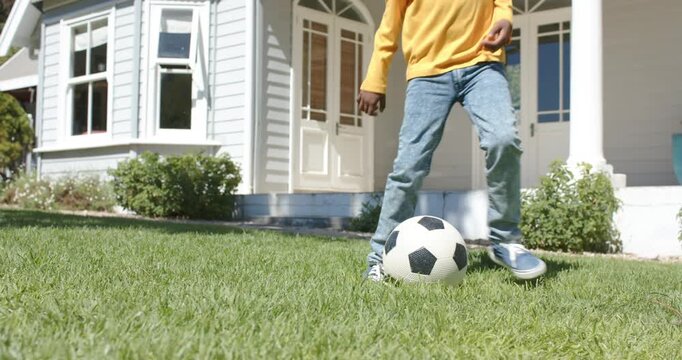 After pause, child is tapping soccer ball, dribbling with step-overs on porch grass, preparing kick