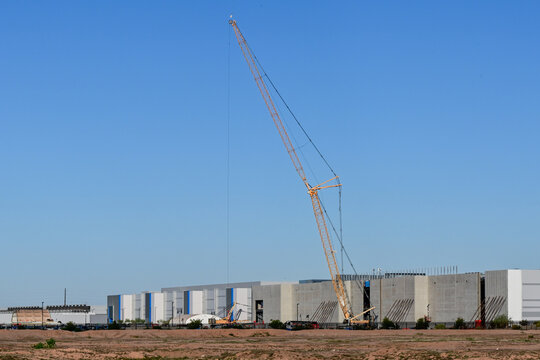 Large industrial building complex under construction with crane at expanding data center campus, representing large scale high tech infrastructure development and hyperscale facility expansion