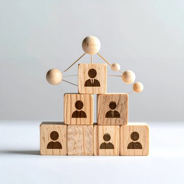 Wooden blocks with person icons forming a pyramid structure, connected by spheres, symbolizing business hierarchy and teamwork.