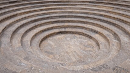 Empty amphitheater circular stone labyrinth center composed concentric spiral-shaped steps made light-colored blocks arranged staggered