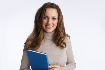 Naklejka premium An approachable professional woman with long brown hair smiles while holding a blue folder, conveying expertise and trustworthiness in a business or educational setting.
