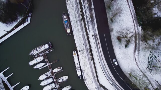 Recreational port in medieval Hanseatic Dutch tower town Zutphen in the Netherlands covered in snow with boats along river IJssel