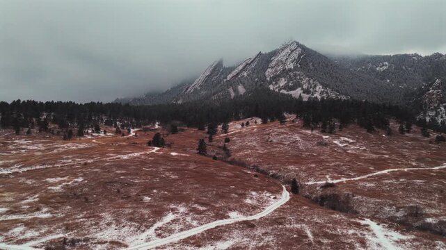 Winter Chautauqua Park trail snowing fog Flat Irons slabs rock formations aerial drone Boulder Colorado sunset dusk evening snowy trees snow falling foggy grey skies low cloud layer upwards motion