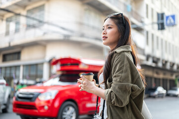 Naklejka premium Asian woman holding coffee while standing or walking aside red bus taxi on road street in local town