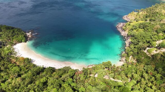 A breathtaking aerial view showcases an idyllic coastal paradise, with pristine turquoise waters embracing a crescent-shaped beach fringed by lush tropical forest.