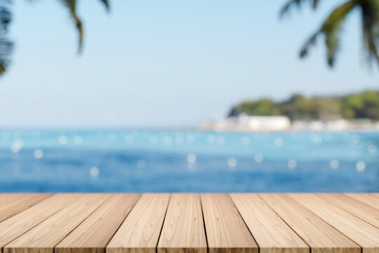 Empty wooden table or plank bench or boardwalk bridge across blue sea and island under summer sky.