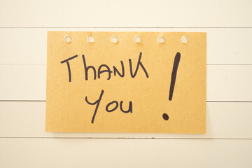 Obraz premium A thank you written on a sticky note. On a white wooden background.