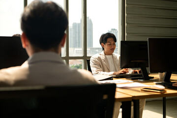 Business team sitting at desks during a meeting, working on computers and reviewing information