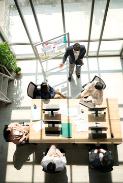 Top view of group business leader presenting information to a team during a meeting