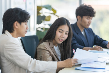 Group of business professionals discussing paperwork, analyzing documents during team meeting in...