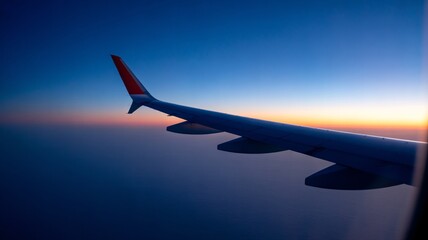 Obraz premium Airplane wing soaring through vibrant sunset sky during flight