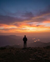 Fototapeta premium Silhouette of Man Watching Sunset Over Mountains and River