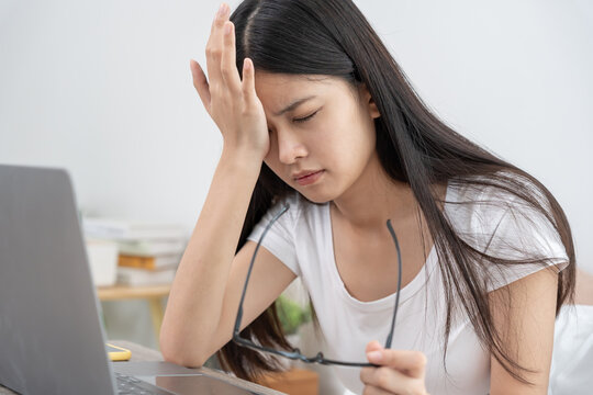 Eye problems, Asian women with tired and irritated eyes, eye rubbing, dry, eye pain after work, migraine, headache, blurred vision, photophobia, working in the dark, blue light from computer