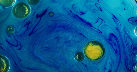 Ink bubbles. Oil water. Defocused blue yellow color shimmer round droplet glitter texture shiny marble liquid floating on abstract art background.