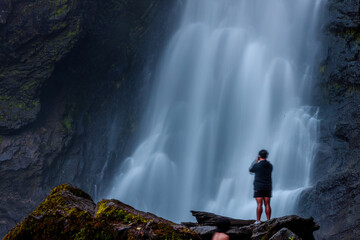 Obraz premium The backdrop of a beautiful natural waterfall in Thailand, Khlong Lan Waterfall in Kamphaeng Phet, features water flowing over a rock formation shaped like a crocodile, surrounded by trees.