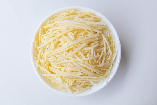 Grated cheese in a bowl isolated on white. Shredded cheddar Cheese in a Bowl, Top view. 