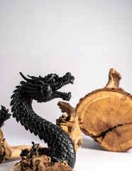 Fototapeta premium Intricate Black Dragon Sculpture with Natural Wood Elements on White Background.