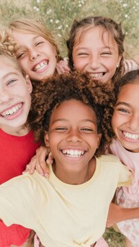 Group of joyful children hugging and smiling outdoors in a home garden during summer vacation, diverse kids enjoying a playful active lifestyle with high angle view