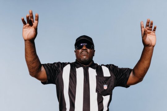 American football referee signaling a touchdown with arms raised while officiating a professional game outdoors including copy space for sports advertising