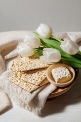 Passover Matzo Bread and Seder Plate with White Tulips on Wooden Table for Holiday Greeting Card and Jewish Celebration Marketing Banner with Copy Space