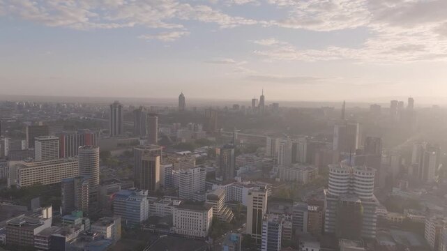 Panoramic aerial drone shot of Nairobi city with the sun setting showcasing the busy streets, matatus, buses, people, and building with the sun setting in the background.