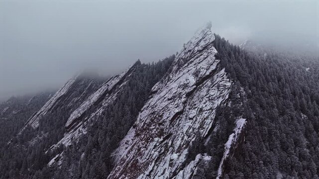 Winter snowing lightly fog Flat Irons rock formations slabs Chautauqua Park trail aerial drone Boulder Colorado sunset dusk evening snowy trees snow falling foggy grey skies low cloud layer circle