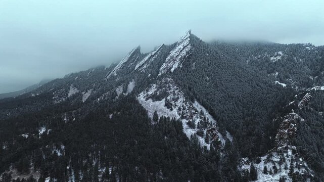 Winter snowing fog Flat Irons rock formations slabs Chautauqua Park trail aerial drone Boulder Colorado sunset dusk evening snowy trees snow falling foggy grey skies low cloud layer forward motion