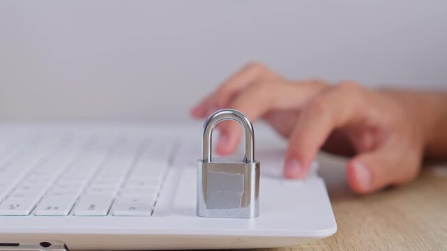Close-up of locked padlock on laptop while person types in background for Cyber security concept