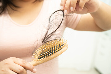 Obraz premium Asian woman have problem with long hair loss attach to comb brush.