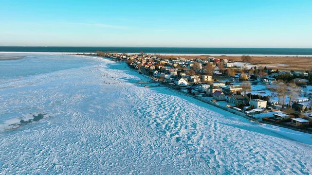 Stunning aerial footage of a frozen sea bay and snowcovered coastal village in Rewa, Poland. Perfect for travel documentaries and winter season concepts.