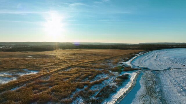 Stunning aerial wide shot of frozen coastal wetlands and snowy beaches in Rewa, Poland during a golden winter sunset. Perfect for travel and nature documentaries.