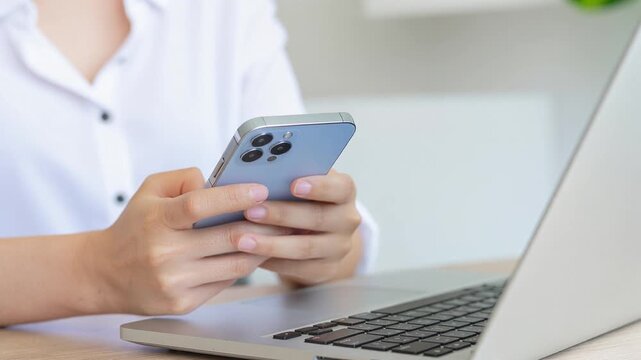 Close up of person using smartphone and laptop for remote work and online communication