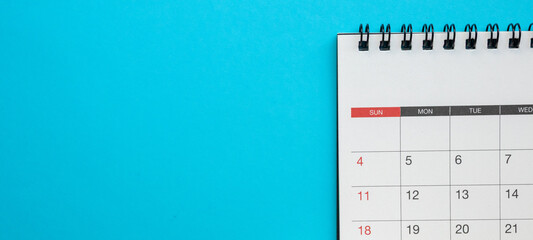 Top view of blank spiral desk calendar on blue background with ample copy space for scheduling