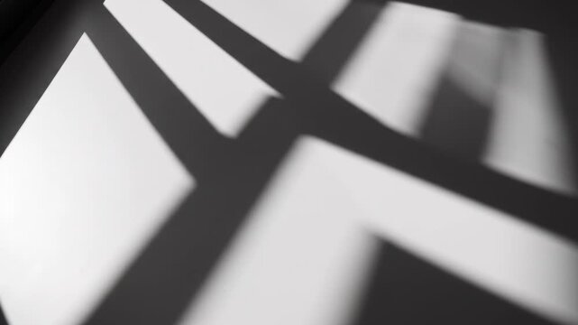 Abstract shadows and light create geometric patterns on a surface.