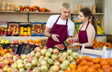 Shop assistants wrap halves of large watermelon in transparent membrane. Customer focus, meeting...