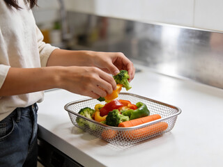 Hands holding broccoli and bell pepper over a basket of vegetables green pepper