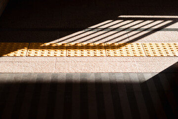 駅構内の点字ブロックと影　バリアフリーの通路背景