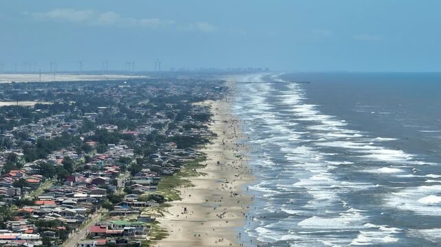 Telephoto 7x drone sideways parallax from ocean to beach city coastline in Cidreira, Brazil.